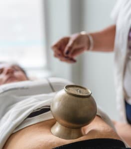 Een koperen navelcup op de buik van een cliënt tijdens een navelcup behandeling